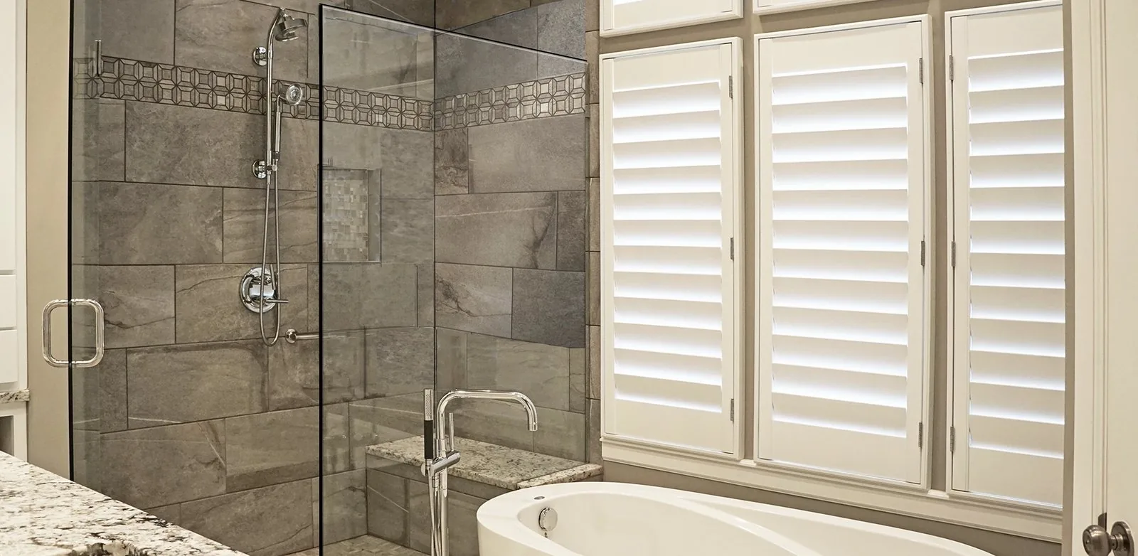 A walk-in shower and a soaking tub beside a shuttered window